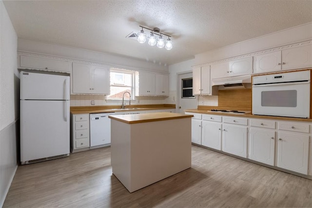 kitchen with a center island, white appliances, white cabinets, sink, and light wood-type flooring