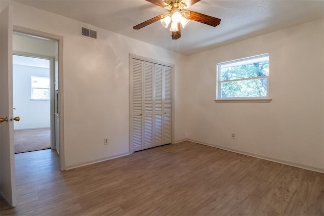 unfurnished bedroom featuring ceiling fan, a closet, and hardwood / wood-style flooring