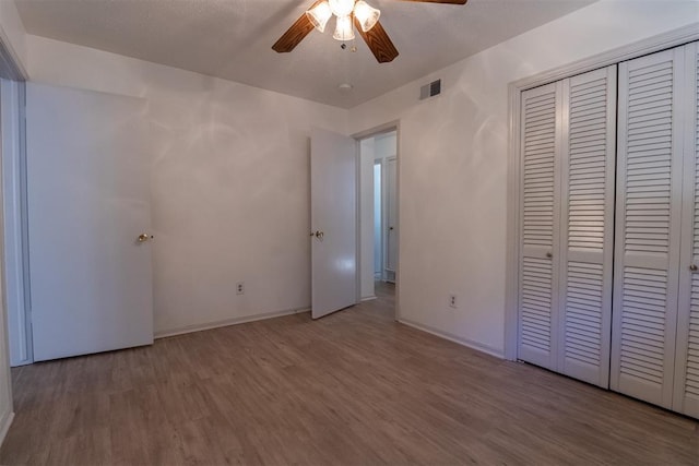 unfurnished bedroom with ceiling fan, light wood-type flooring, and a closet