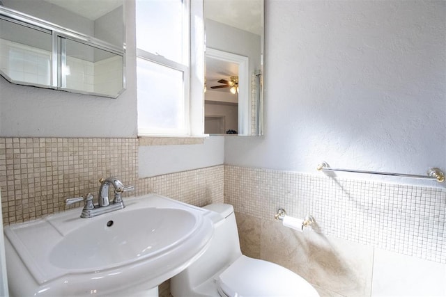 bathroom featuring ceiling fan, toilet, tile walls, and sink