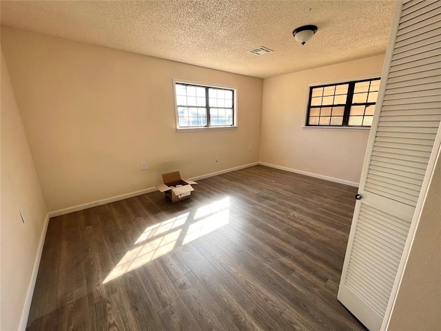 unfurnished room featuring a textured ceiling and dark hardwood / wood-style floors