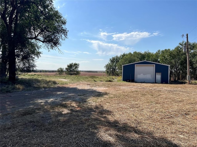 view of yard featuring an outbuilding, a rural view, and a garage