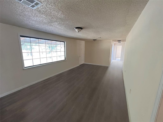 spare room featuring a textured ceiling and dark wood-type flooring