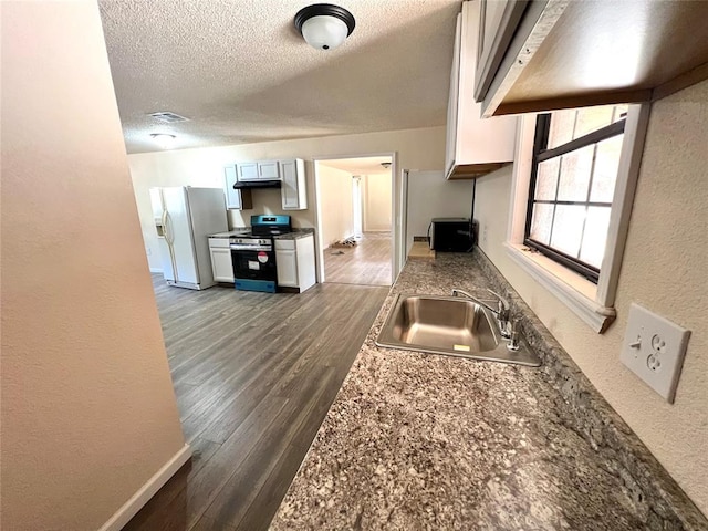 kitchen featuring black gas range oven, a textured ceiling, dark wood-type flooring, sink, and white fridge with ice dispenser