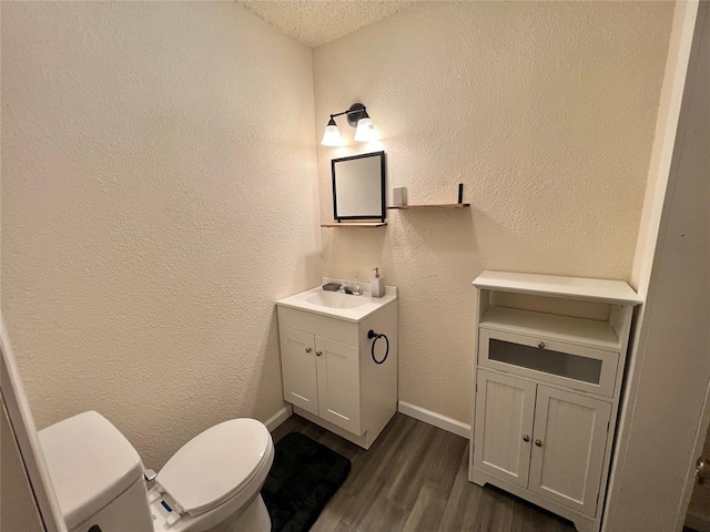 bathroom with vanity, toilet, wood-type flooring, and a textured ceiling