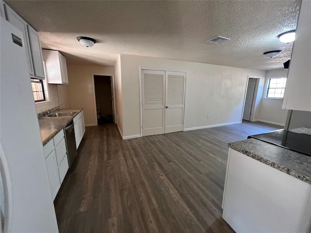 kitchen featuring sink, stainless steel dishwasher, dark hardwood / wood-style floors, a textured ceiling, and white cabinetry