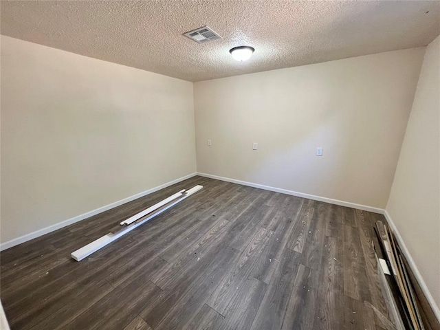 empty room featuring dark hardwood / wood-style flooring and a textured ceiling