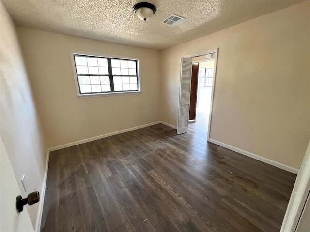 unfurnished room featuring dark wood-type flooring and a textured ceiling