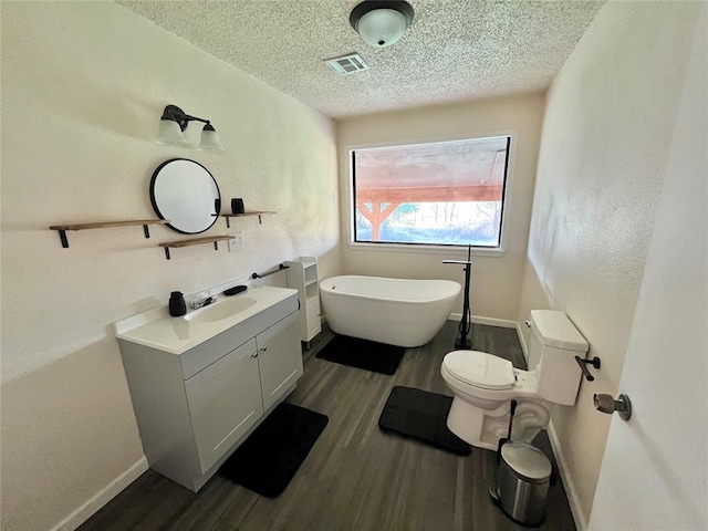 bathroom with a bathing tub, vanity, wood-type flooring, and a textured ceiling