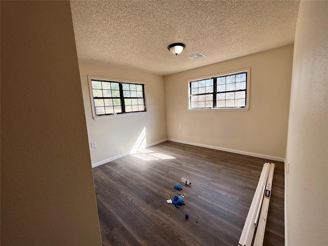 unfurnished room with a textured ceiling and dark hardwood / wood-style floors