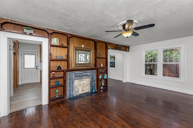 unfurnished living room featuring a textured ceiling, dark hardwood / wood-style floors, a wealth of natural light, and ceiling fan