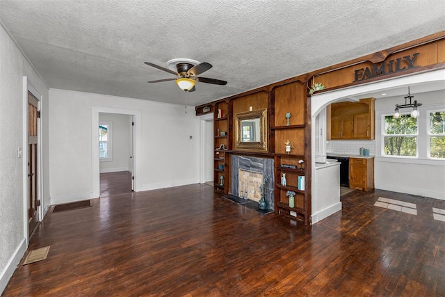 unfurnished living room with a textured ceiling, dark hardwood / wood-style flooring, ceiling fan, and a premium fireplace