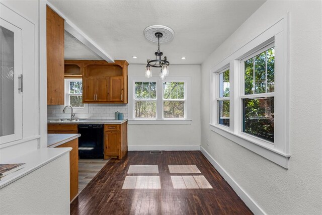 kitchen with black dishwasher, decorative light fixtures, a wealth of natural light, and dark wood-type flooring