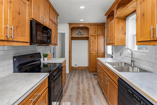 kitchen with light wood-type flooring, decorative backsplash, sink, and black appliances