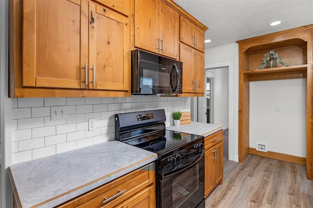 kitchen featuring tasteful backsplash, black appliances, and light wood-type flooring