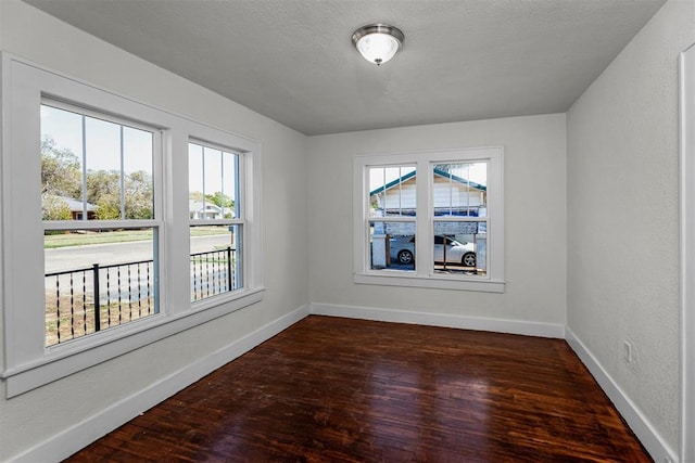 empty room with dark hardwood / wood-style flooring and a textured ceiling