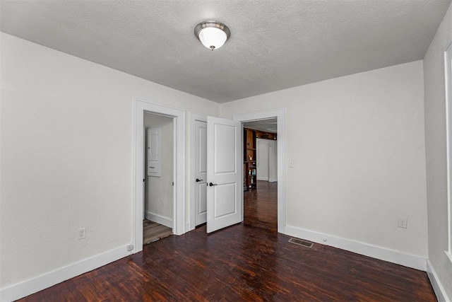 unfurnished bedroom featuring a textured ceiling and dark hardwood / wood-style flooring