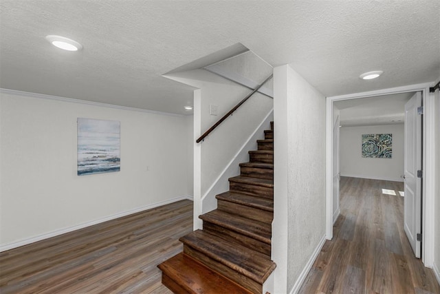 stairway featuring crown molding, hardwood / wood-style floors, and a textured ceiling