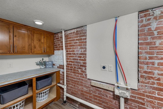 kitchen with a textured ceiling, light hardwood / wood-style floors, and brick wall