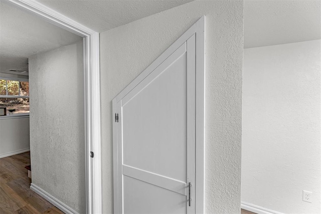 hallway with a textured ceiling and dark wood-type flooring