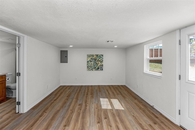 interior space featuring electric panel, hardwood / wood-style floors, and a textured ceiling