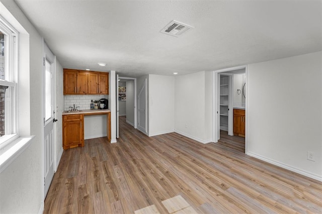 kitchen with decorative backsplash, light hardwood / wood-style flooring, and sink