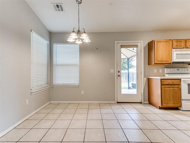 kitchen with light tile patterned floors, pendant lighting, white appliances, and an inviting chandelier