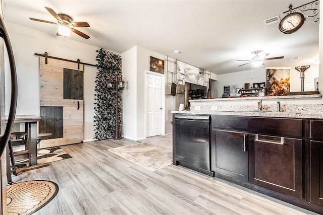 kitchen featuring dishwasher, ceiling fan, a barn door, light hardwood / wood-style floors, and dark brown cabinetry