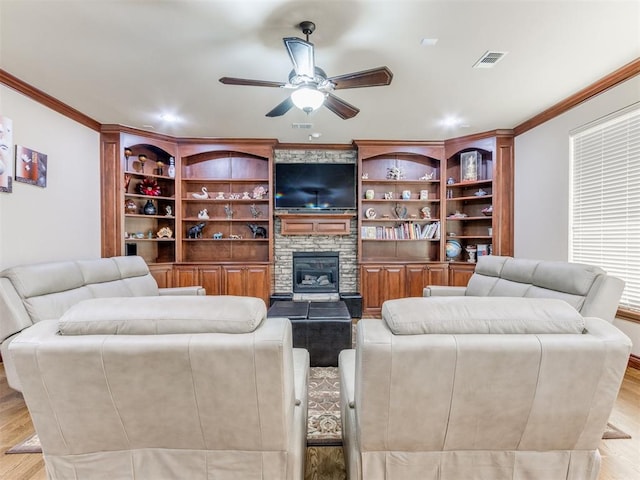 living room with light hardwood / wood-style flooring, ceiling fan, crown molding, and a stone fireplace