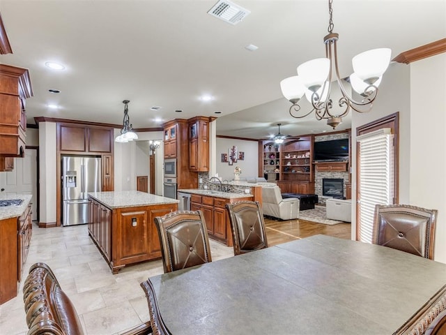 dining space with ceiling fan with notable chandelier, sink, ornamental molding, and a fireplace