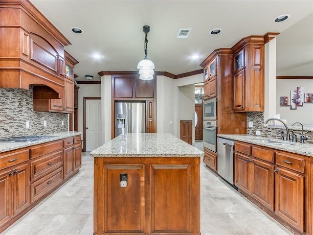 kitchen featuring sink, light stone counters, decorative light fixtures, a kitchen island, and appliances with stainless steel finishes