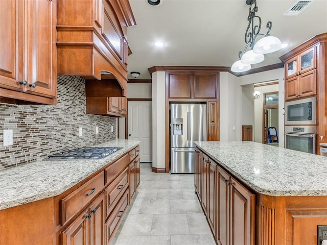 kitchen with appliances with stainless steel finishes, tasteful backsplash, ornamental molding, decorative light fixtures, and a kitchen island