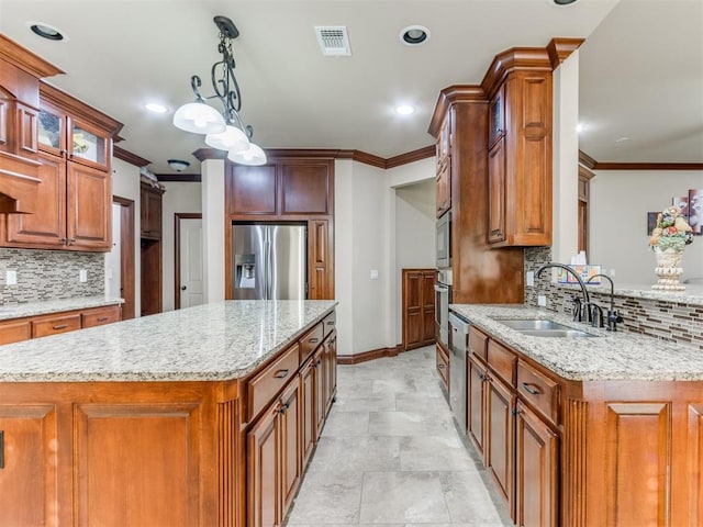 kitchen with pendant lighting, light stone counters, sink, and stainless steel appliances