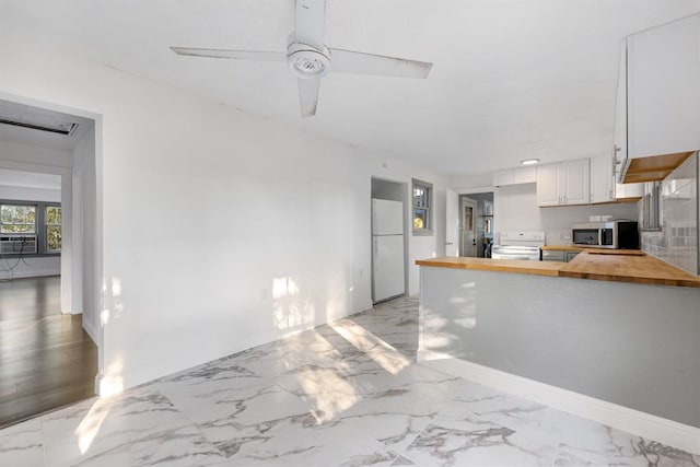 kitchen featuring white appliances, white cabinets, ceiling fan, wood counters, and kitchen peninsula