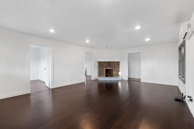 unfurnished living room featuring a wall mounted air conditioner, a stone fireplace, and dark hardwood / wood-style floors