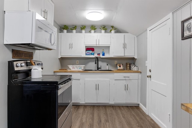 kitchen featuring stainless steel electric range oven, white microwave, a sink, white cabinets, and light wood-style floors