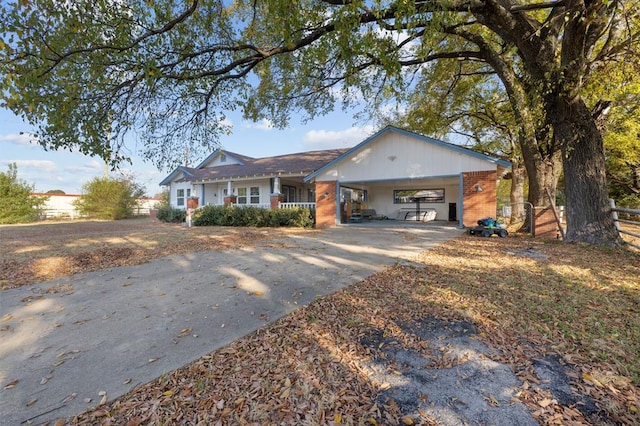 single story home featuring brick siding, an attached carport, fence, covered porch, and driveway