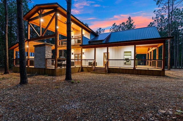 back house at dusk featuring a porch and a balcony