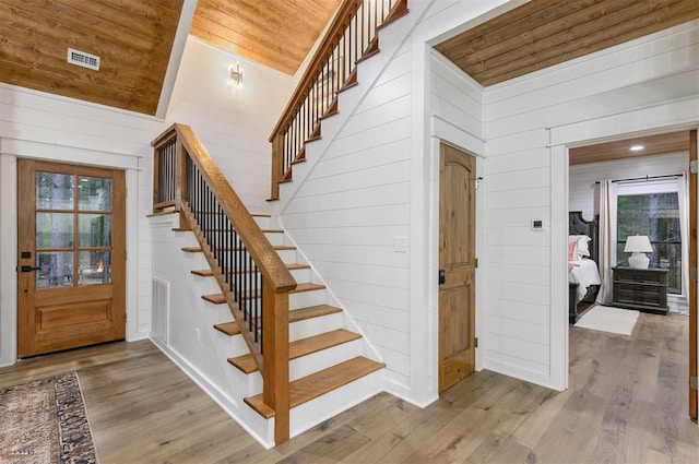 stairs with wood-type flooring, wood walls, and wood ceiling