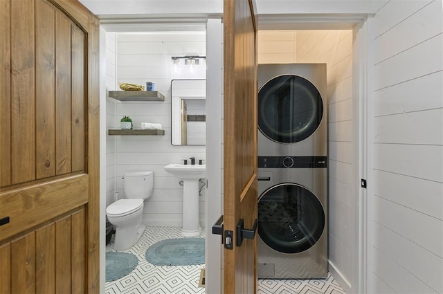 bathroom with tile patterned flooring, toilet, and stacked washer / dryer