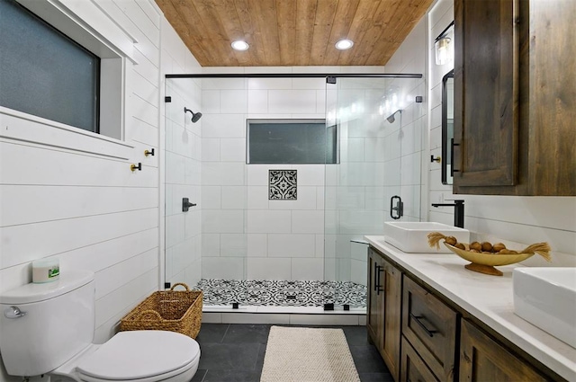 bathroom featuring vanity, tile patterned flooring, toilet, tile walls, and a shower with shower door