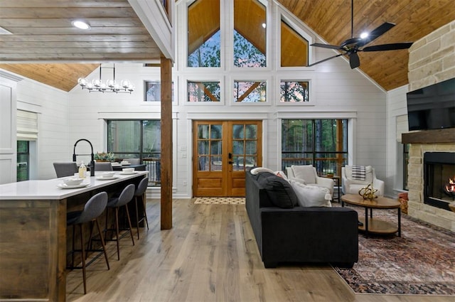 living room featuring french doors, wooden ceiling, high vaulted ceiling, wood walls, and light wood-type flooring