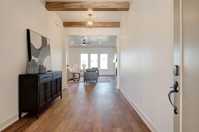 hallway with dark wood-style flooring, beam ceiling, and baseboards