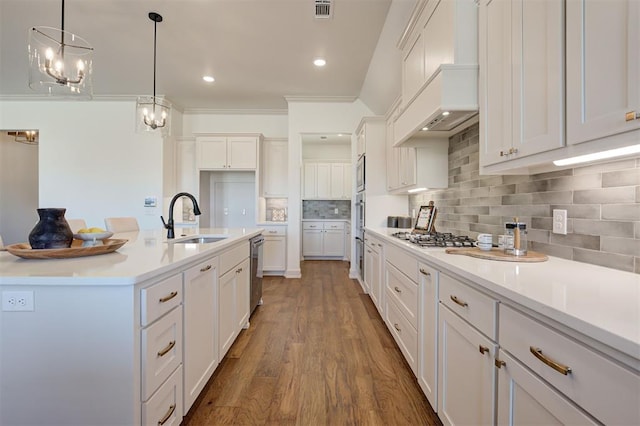 kitchen with tasteful backsplash, visible vents, white cabinetry, a sink, and wood finished floors