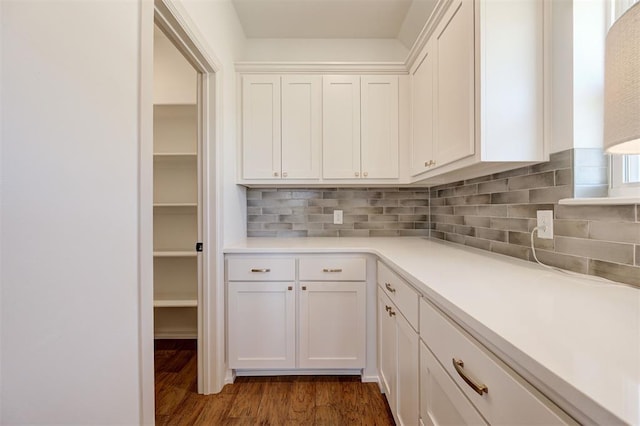 interior space with tasteful backsplash, white cabinetry, light countertops, and dark wood-type flooring