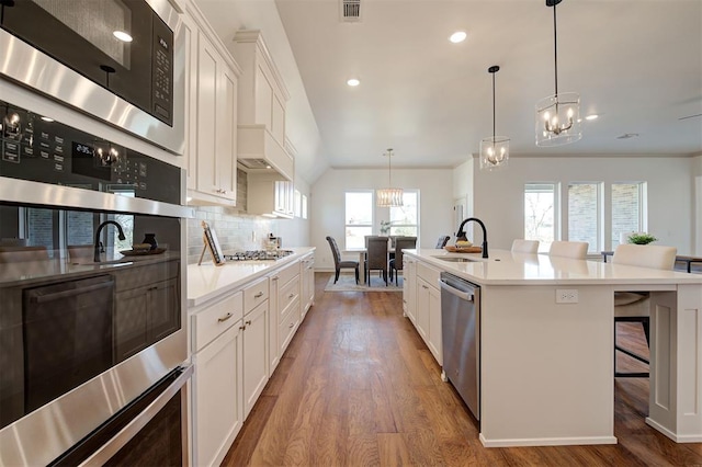 kitchen with wood finished floors, appliances with stainless steel finishes, a sink, and tasteful backsplash