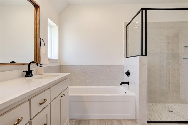 full bathroom featuring lofted ceiling, wood finished floors, vanity, a shower stall, and a bath