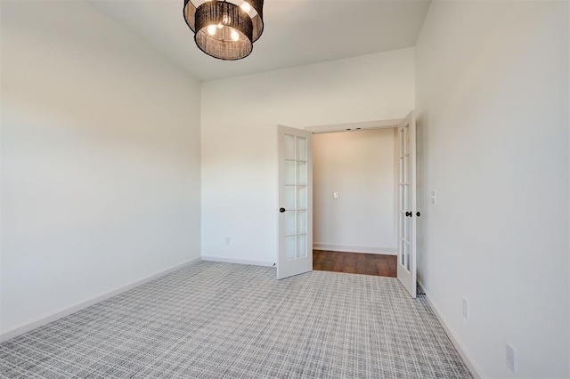 carpeted empty room featuring baseboards and french doors