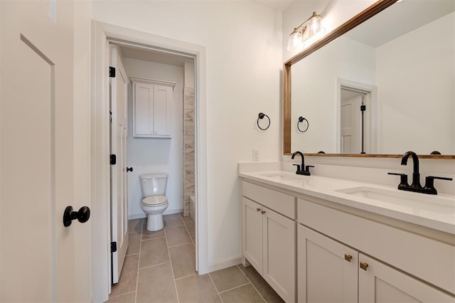 bathroom with double vanity, tile patterned flooring, a sink, and toilet