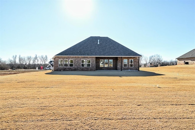 rear view of house with brick siding and a yard